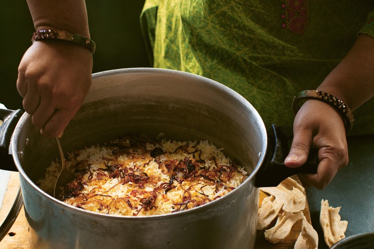Chef preparing biryani in traditional pot